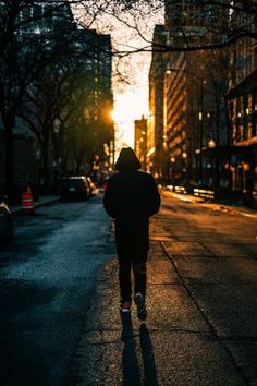 a person walking down the street at sunset