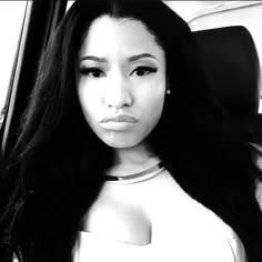 a black and white photo of a woman with long hair in a car looking at the camera