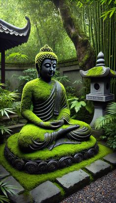 a buddha statue sitting in the middle of a lush green area with trees and bushes