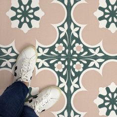 a person standing on a tiled floor with their feet propped up against the ground and wearing white sneakers