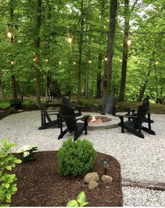 an outdoor fire pit surrounded by chairs and trees with lights strung over the seating area