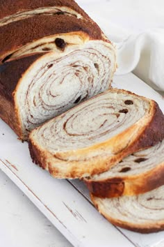 a loaf of cinnamon swirl bread sitting on top of a cutting board next to a white towel