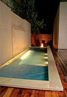 a small pool in the middle of a wooden decked area with lights on it