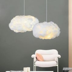 two clouds are hanging from the ceiling above a white chair and table in front of a gray wall