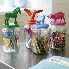 four jars with different colored pencils and animal figurines in them on a table