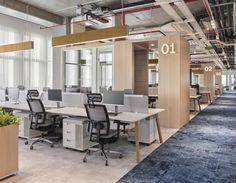 an open office space with desks and plants in the center, along with large windows