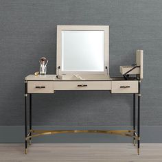 a dressing table with a mirror, stool and other items on it in front of a gray wall