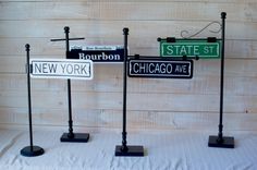 three black and white street signs sitting on top of a bed next to each other