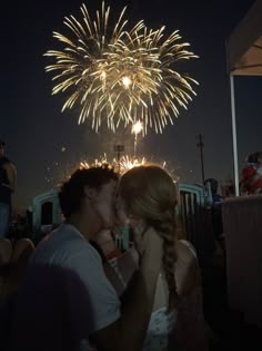 a man and woman kissing in front of fireworks