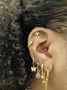 a close up of a person's ear with gold jewelry on it and her hair in the background