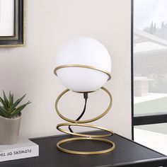 a lamp sitting on top of a table next to a potted plant