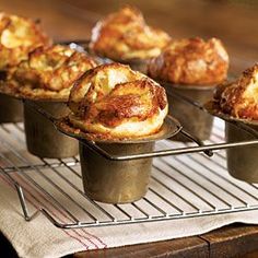 several muffins sitting in metal pans on top of a cooling rack next to each other