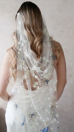 a woman wearing a white veil with flowers on it and a blue butterfly in the back