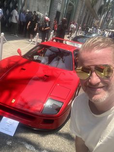 a man standing next to a red sports car