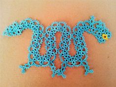 a blue crocheted bracelet with flowers on the end and an attached chain around it