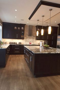 a large kitchen with dark cabinets and marble counter tops