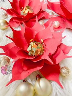 red paper poinsettis on white fur with gold balls and ornaments around them