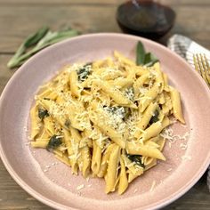 pasta with spinach and parmesan cheese in a pink plate on a wooden table