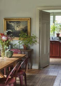 an image of a dining room with flowers in vases on the table and pictures on the wall