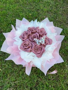 a bouquet of pink roses in the grass with a butterfly on it's back