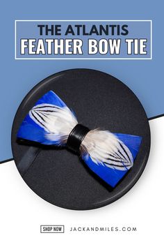 A stylish feather bow tie featuring bold blue and white hues with intricate black patterns, secured by a black leather band, lying against a black background.