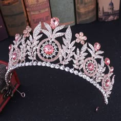 a tiara with pink and white stones on it, sitting next to some books