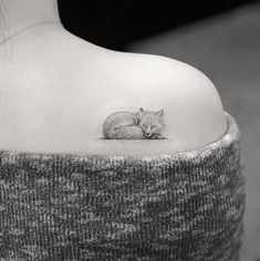 a black and white photo of a woman's shoulder with a small fox tattoo on it