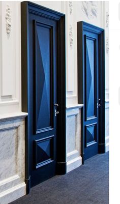 two blue doors are next to each other in an empty room with marble floors and walls