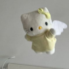 a hello kitty stuffed animal hanging from the ceiling in front of a computer monitor and keyboard