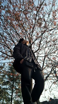 a man standing in front of a tree with his back to the camera and looking up