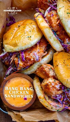 a basket filled with chicken sandwiches next to a bowl of dipping sauce