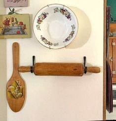 there is a wooden spoon hanging on the wall next to a plate and utensils