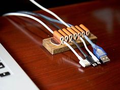 an electronic device connected to a laptop on a wooden table next to a white keyboard