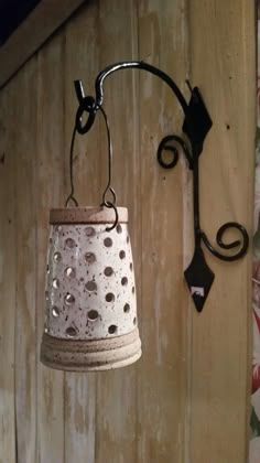 an old fashioned light hanging from the side of a wooden wall next to a flowered curtain