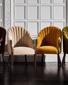 three different colored chairs sitting next to each other on top of a hard wood floor