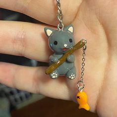 a person holding a tiny keychain with a cat on it's back