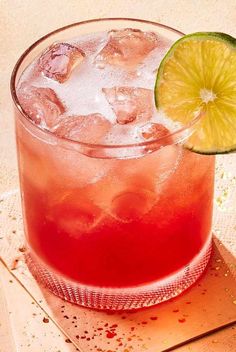 a close up of a drink in a glass with a lime slice on the rim