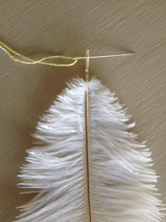 a white feather is being hooked up to a hook on the wall by a string