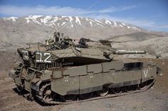 an army tank sitting on top of a dirt field in front of a snow covered mountain