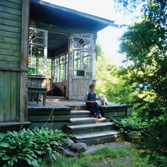 a young boy sitting on steps with his dog in front of a cabin style house