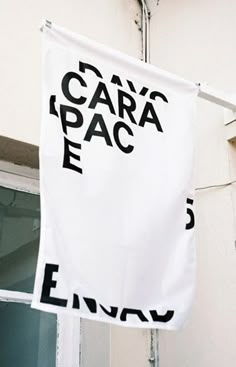 a white banner hanging from the side of a building with black lettering on it that says cara's place