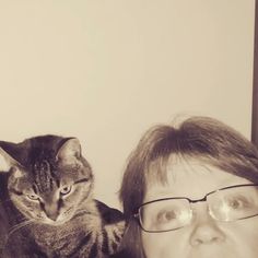 a woman with glasses and a cat on her shoulder