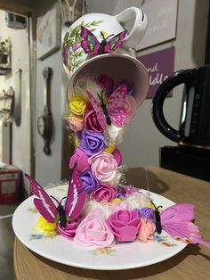 a plate with flowers and butterflies on it sitting on a table next to a microwave