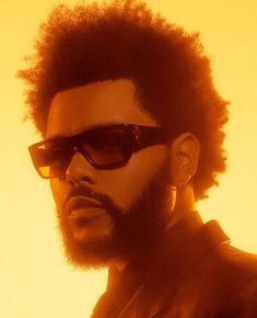 a close up of a person wearing sunglasses with an afro haircut and beard in front of a yellow background