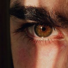 a close up of a persons eye with long black hair on top of his eyebrows