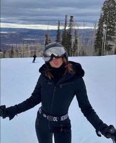 a woman on skis in the snow with her hands out and wearing goggles