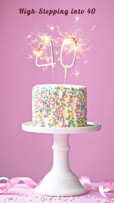 a birthday cake with sprinkles and sparklers on top, sitting on a pedestal