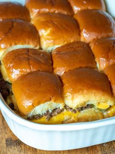 a casserole dish filled with cheeseburger sliders on top of a wooden table