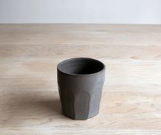 a black cup sitting on top of a wooden table