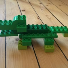 a green lego alligator sitting on top of a wooden floor